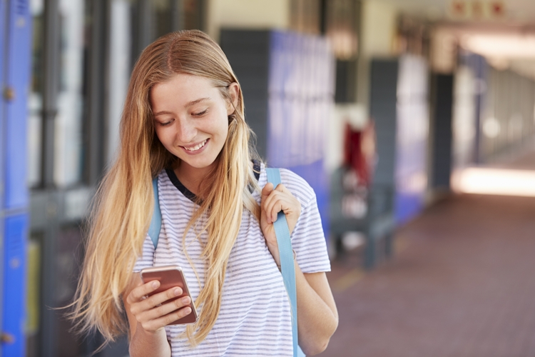 Happy teenage girl using smartphone